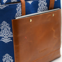 Blue floral-patterned tote bag with brown leather accents on a white background