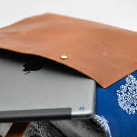 Tablet in a brown leather and blue fabric case with white floral patterns.