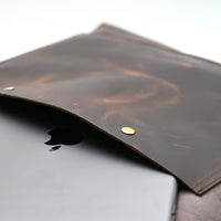 Brown leather sleeve with gold buttons on a laptop