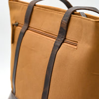 Brown tote bag with black straps on a white background