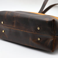 Brown leather bag with gold rivets on a white background
