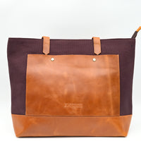 Two-toned brown leather tote bag with visible brand name on a white background