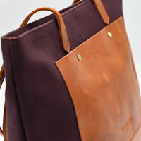 Brown leather tote bag with a visible brand name on a white background