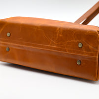 Brown leather bag with visible wear on a white background