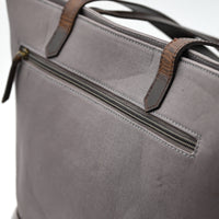 Gray bag with brown leather straps on a light gray background