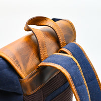 Close-up of a brown leather and blue fabric bag on a white background