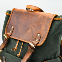 Green backpack with brown leather accents on a white background