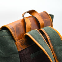 Green backpack with brown leather straps on a white background