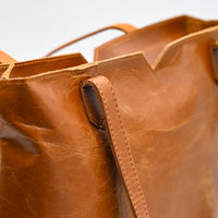Brown leather tote bag on a light gray background