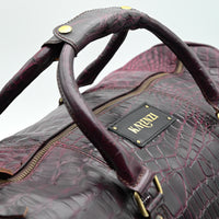 Brown leather duffel bag with gold accents on a light gray background