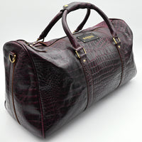 Brown leather duffel bag with crocodile texture on a white background