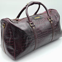 Brown leather duffel bag with crocodile texture on a white background