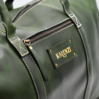 Green leather duffel bag with 'KARINZI' brand label on a blurred background