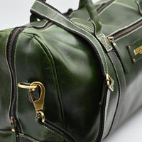 Green leather duffel bag with gold hardware on a white background