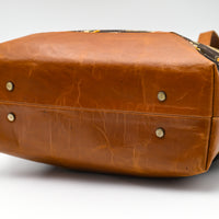 Brown leather bag with a patterned strap on a white background