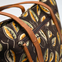Patterned bag with brown leather straps on a light gray background