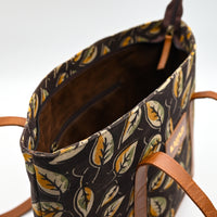 Patterned handbag with brown handles on a white background