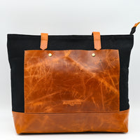 Brown leather tote bag with black sides on a white background