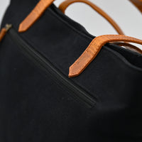 Black bag with brown leather straps on a neutral background