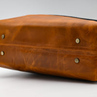 Brown leather bag with visible stitching on a white background