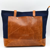 Tote bag with brown leather front and navy sides on a white background