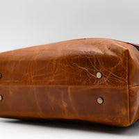 Brown leather bag with visible wear on a white background