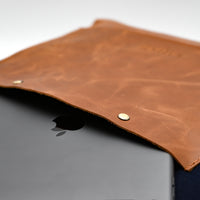 Brown leather sleeve on a laptop with a blurred background