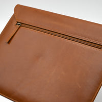 Brown leather envelope with a zipper on a white background