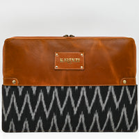 Brown leather clutch with black and white patterned fabric on a white background