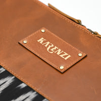 Brown leather pouch with 'KARENZI' label on a patterned fabric background