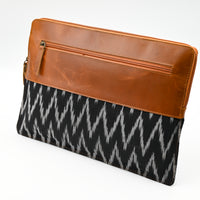 Clutch bag with brown leather top and black patterned fabric on a white background