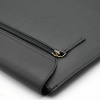 Black leather clutch with gold zipper on a white background