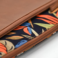 Close-up of a brown leather case with a colorful leaf pattern on a white background