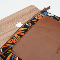Two laptop sleeves, one with a wooden texture and Apple logo, the other with a floral pattern and 'KARENZI' branding, on a white background.