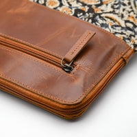Brown leather wallet with zipper on a patterned fabric background