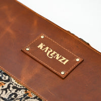 Brown leather wallet with 'KARENZI' brand label on a patterned fabric background