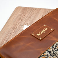 Brown leather wallet with 'Karezi' brand name on a wooden and patterned fabric background