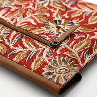 Floral patterned clutch bag with brown trim on a white background